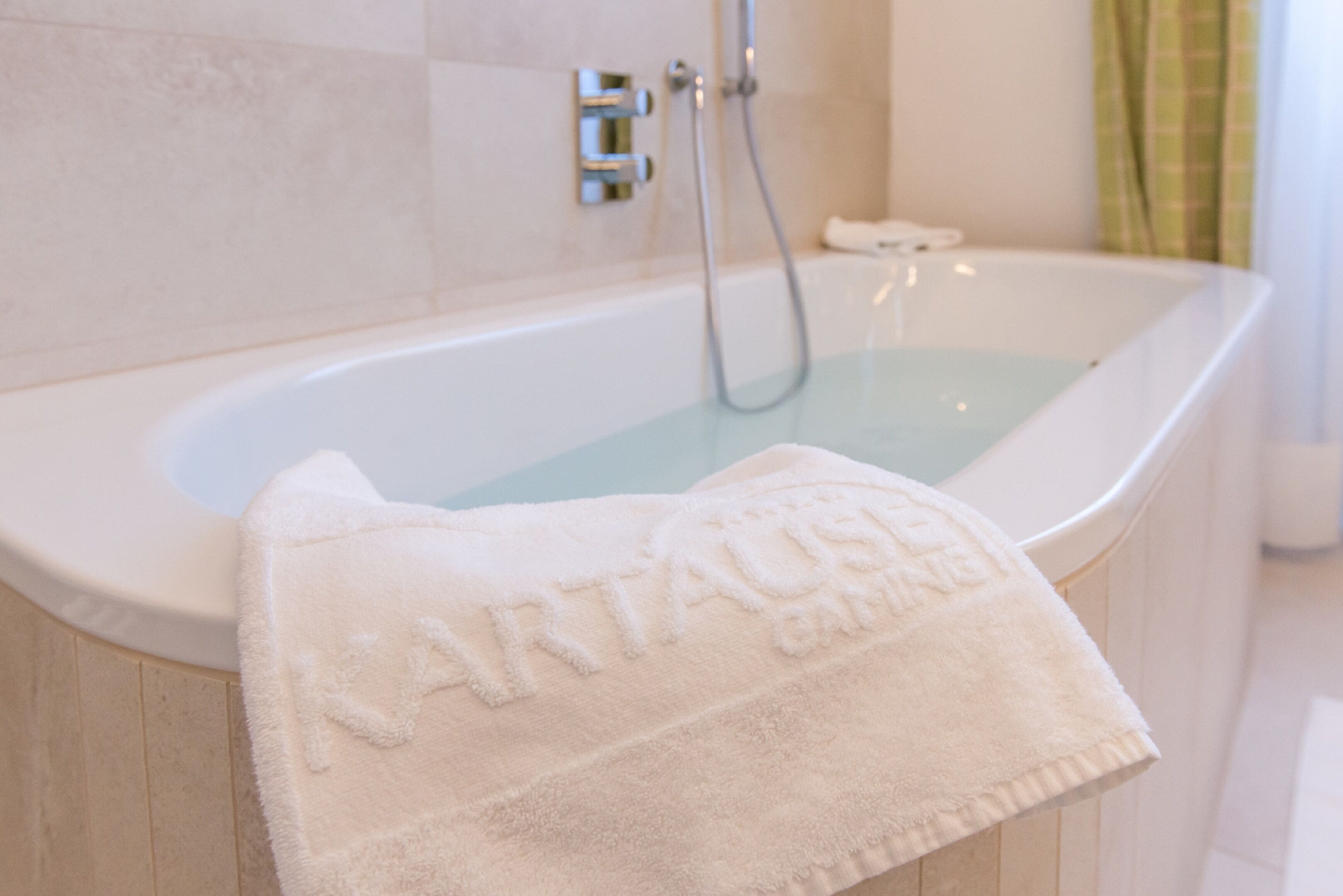 A white bathtub with a towel labeled "Nartaush Spa" and a showerhead.