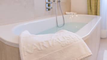 A white bathtub with a towel labeled "Nartaush Spa" and a showerhead.