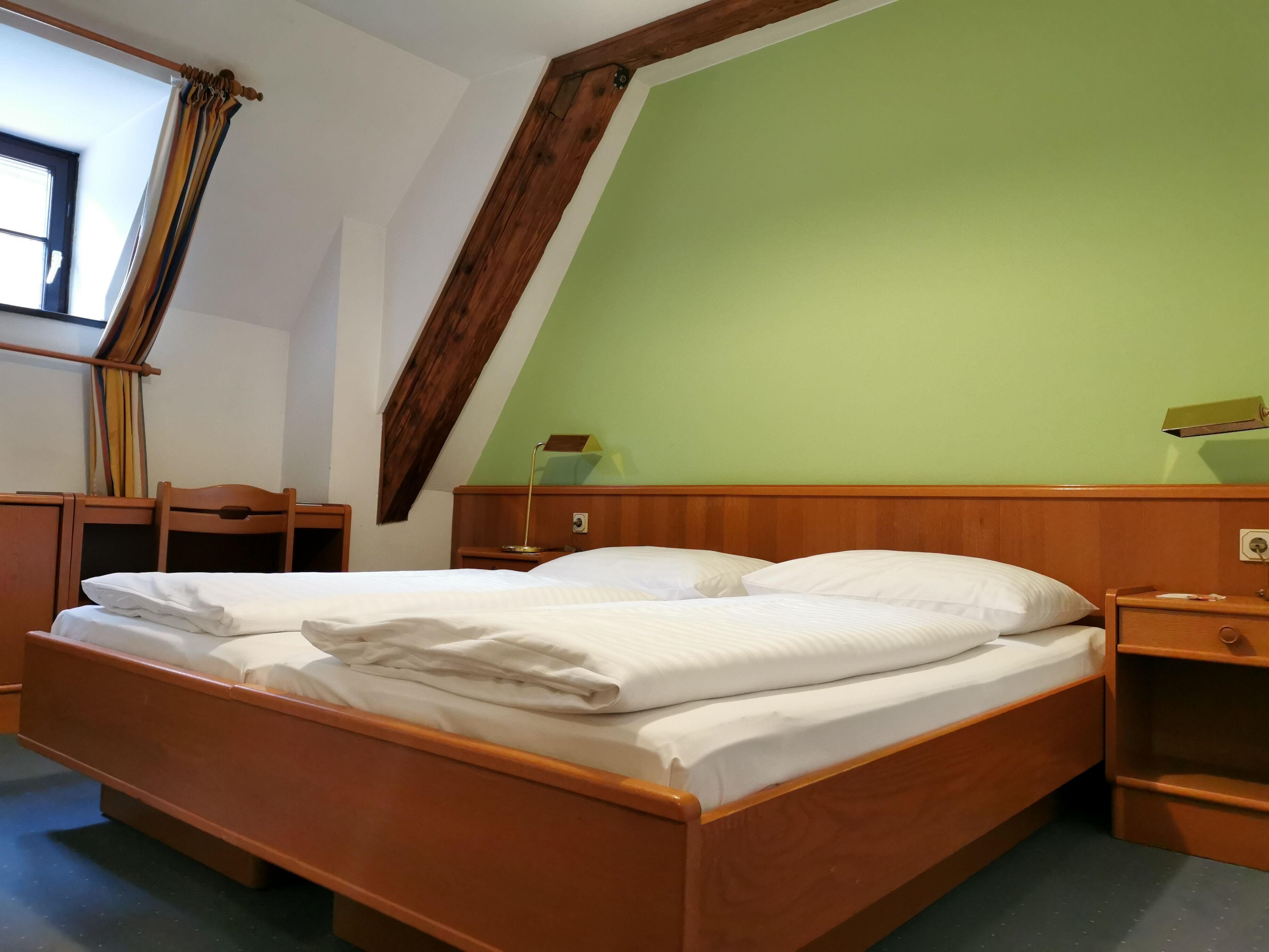 Een kamer met een houten bed, een bureau en een stoel.