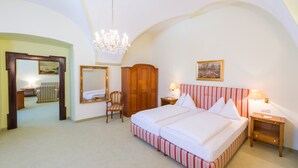 A bedroom with a large bed, a wooden wardrobe, a chair, a mirror, and a chandelier. - Hotel Kartause (Gaming)