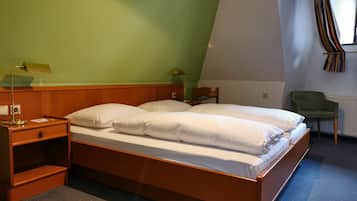 Un dormitorio con una cama de madera, una mesita de noche, una lámpara, una silla y una ventana con cortinas.