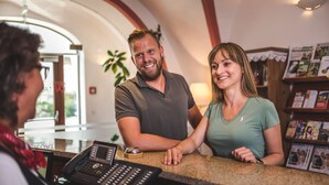 A reception area with a counter, a phone, and a small plant. - Hotel Kartause (Gaming)