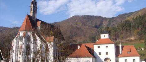 Eine Kirche mit einem hohen Kirchturm und ein kleineres Gebäude mit rotem Dach im Vordergrund.