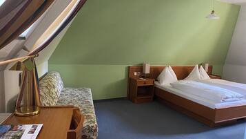 Una habitación de hotel con una cama, un escritorio con teléfono, una mesita de noche y una lámpara.