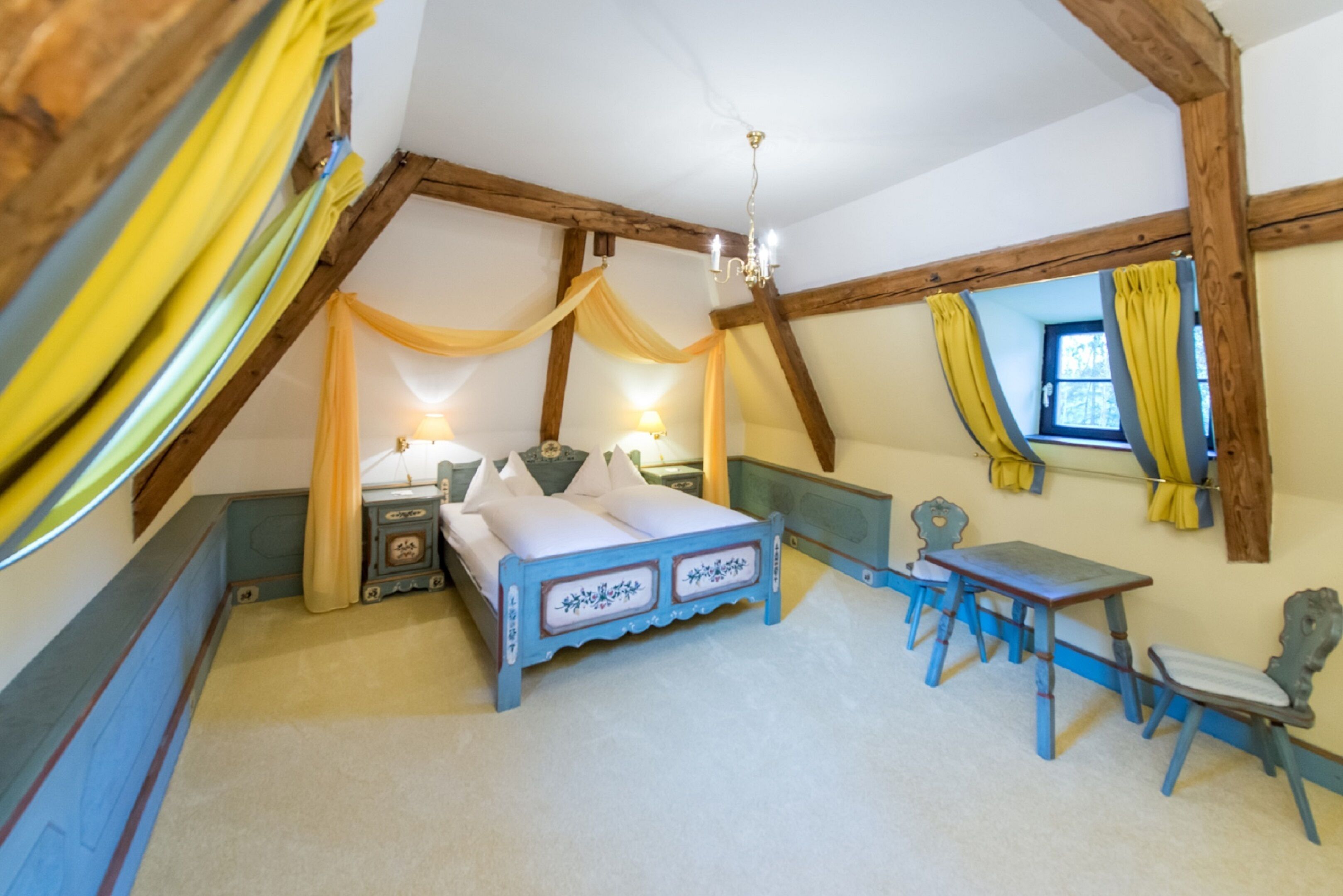 A bedroom with a bed, bedside tables, a desk, and chairs.