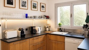 Une cuisine moderne avec des meubles en bois, un lave-vaisselle blanc et une fenêtre donnant sur un paysage verdoyant.