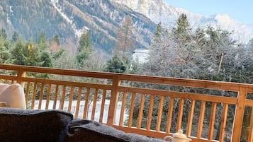 A balcony with a view of snow-capped mountains and trees.