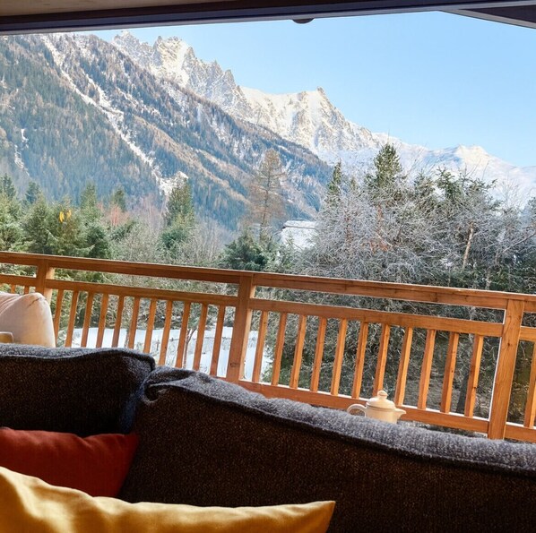 A balcony with a view of snow-capped mountains and trees.