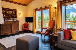 A cozy living room with a fireplace, a television, and a balcony with a mountain view.