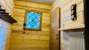 L’intérieur d’une cabane en bois, avec une fenêtre, un radiateur et un thermomètre fixé au mur.