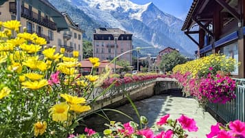 A hotel with a view of snow-capped mountains, a bridge, and colorful flowers.