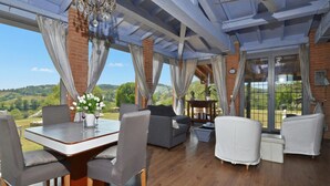 Una habitación amplia con una mesa de comedor, sillas, sofás y vistas al campo.