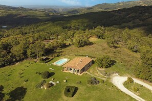 A house with a swimming pool, surrounded by lush greenery and hills.