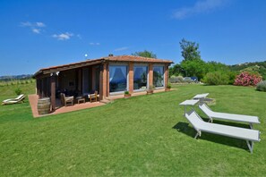 A house with a patio, lounge chairs, and a garden.