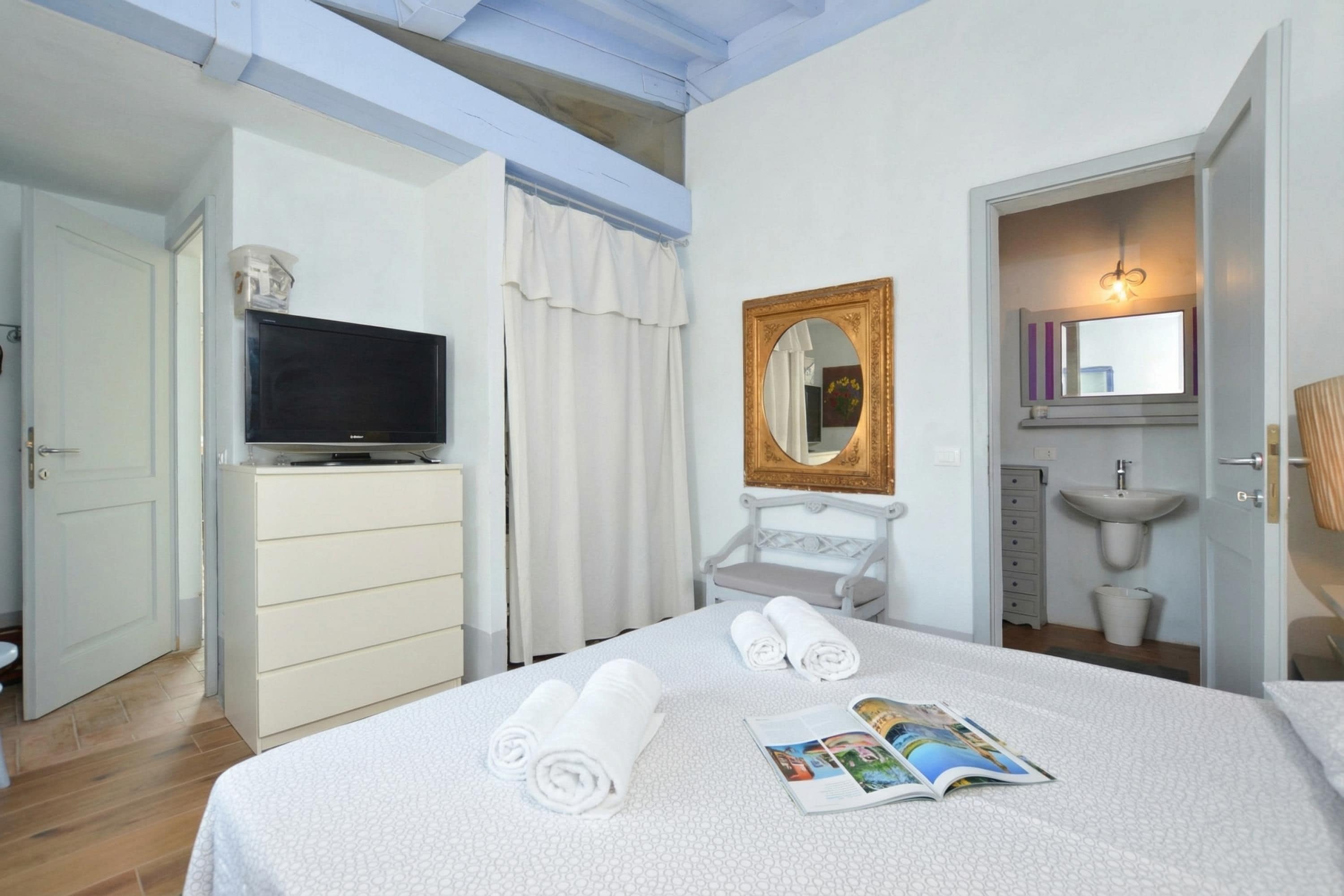 Une chambre d’hôtel avec un lit, une télévision, un miroir, une salle de bain et une vue sur le ciel.