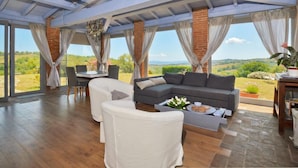 Amplia sala de estar con sofá seccional, una mesa de comedor y vistas al campo.
