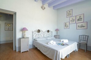 A bedroom with a bed, two bedside tables, a chair, and wall art. - Villa Borgiano (Scansano)