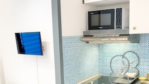 A compact kitchen with a microwave, a small sink, and a tiled backsplash. - Cosy Nest Near Center Chamonix (Chamonix-Mont-Blanc)