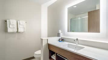 Une salle de bain moderne avec un lavabo blanc, un meuble-lavabo en bois et un grand miroir.