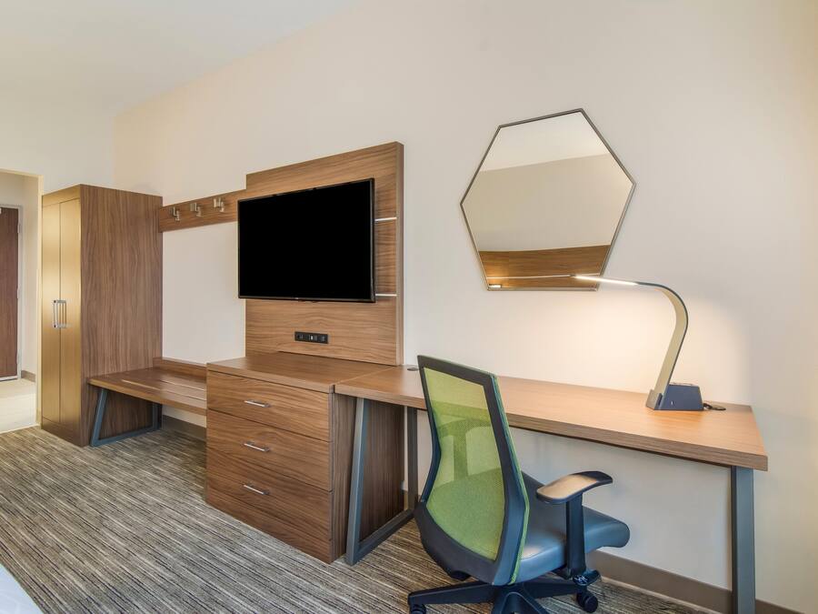 Une chambre d’hôtel avec un bureau en bois, une télévision, un miroir et une chaise.