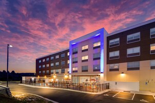 Un hotel moderno de varios pisos, con terraza al aire libre y zona de estacionamiento.