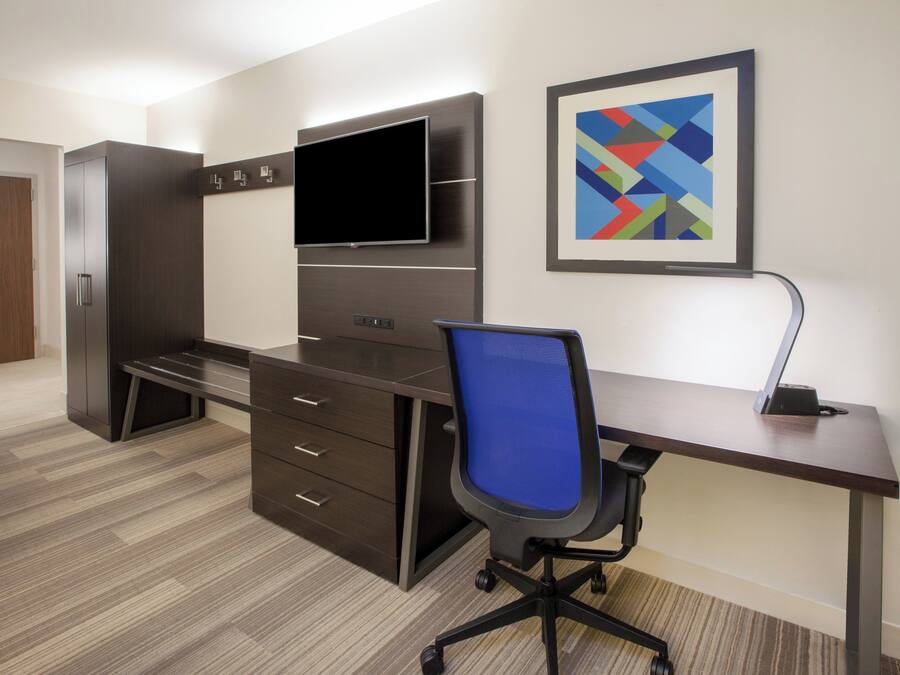 A modern office space with a desk, chair, and a flat-screen TV mounted on the wall.