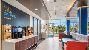 L’intérieur d’un café, avec un comptoir, des machines à café, un espace salon et une vue à travers les portes vitrées.