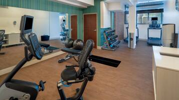 A gym with cardio equipment, weight machines, and a mirror.