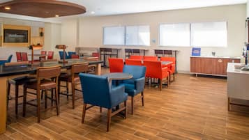 Un espace repas moderne avec un plancher en bois, des chaises rouges et bleues, et une table centrale.