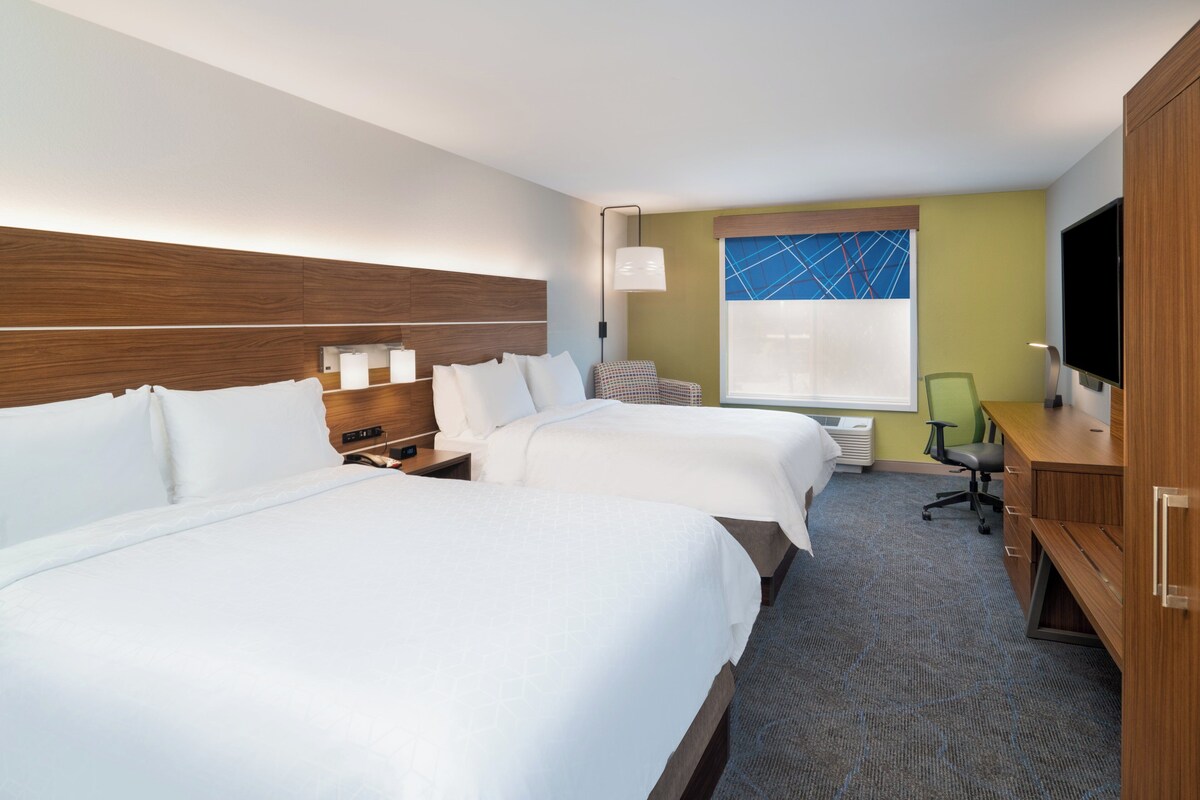 Une chambre d’hôtel avec deux lits, un bureau, une chaise, une télévision et une fenêtre donnant sur un beau paysage.