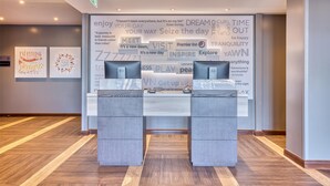 Una reception con un grande pannello motivazionale alle spalle, con diverse citazioni ispiratrici e il logo Premier Inn.