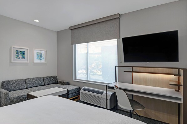 A hotel room with a bed, a sofa, a desk, a chair, a TV, and two framed pictures on the wall. - TownePlace Suites by Marriott Sumter (Sumter)