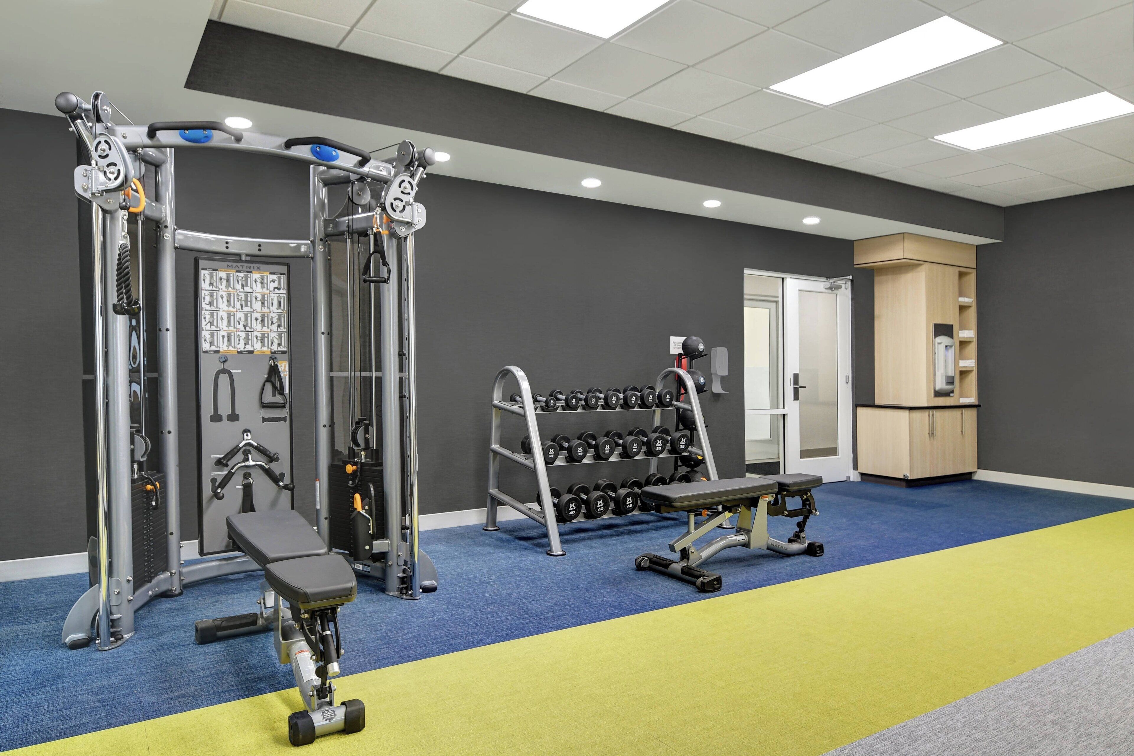 Une salle de sport équipée de matériel de musculation, de bancs et d’haltères.