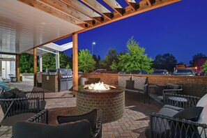 An outdoor patio area with a fire pit, seating, and a covered section with a grill. - TownePlace Suites by Marriott Sumter (Sumter)