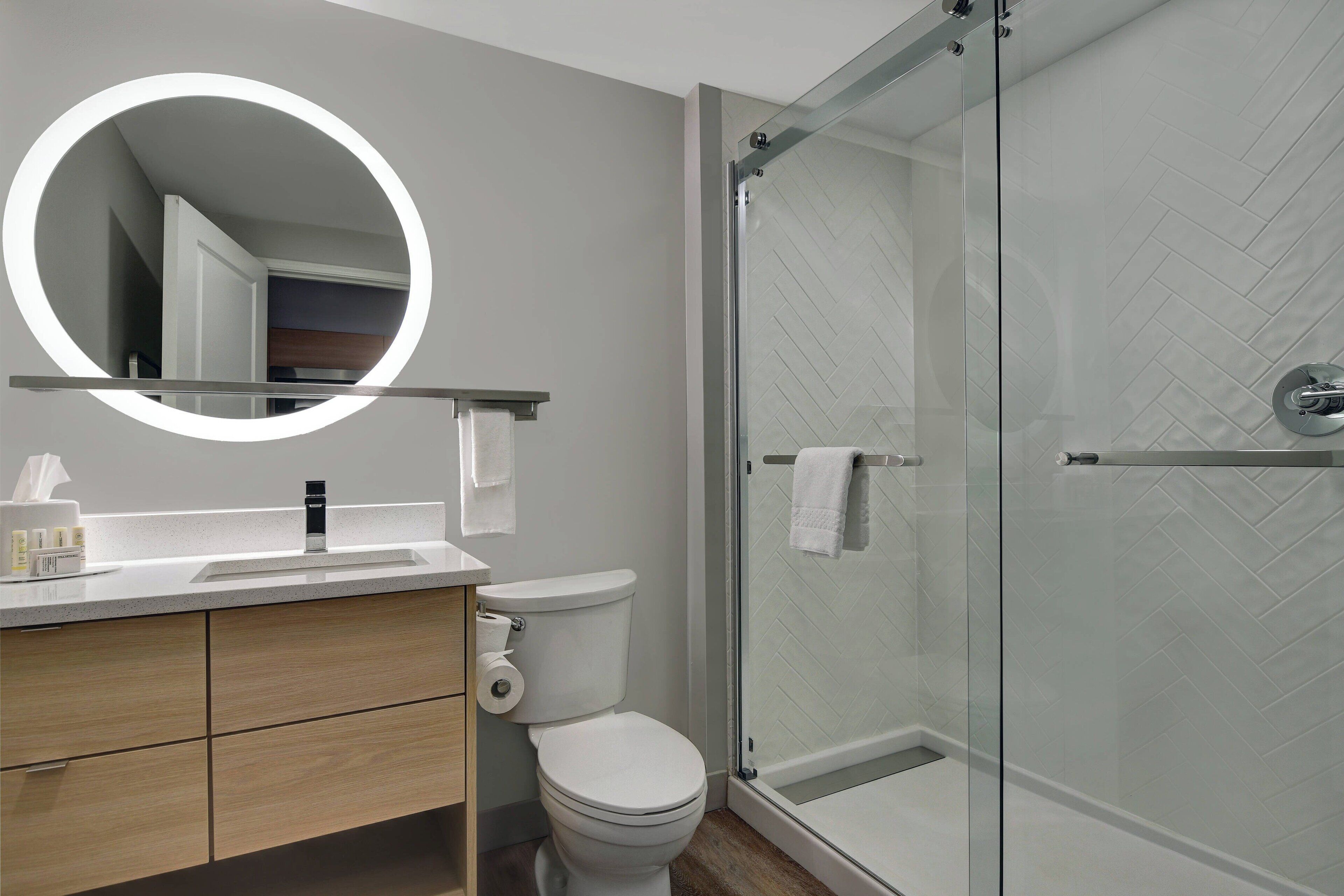 Un baño moderno con inodoro, lavamanos y cabina de ducha de vidrio.