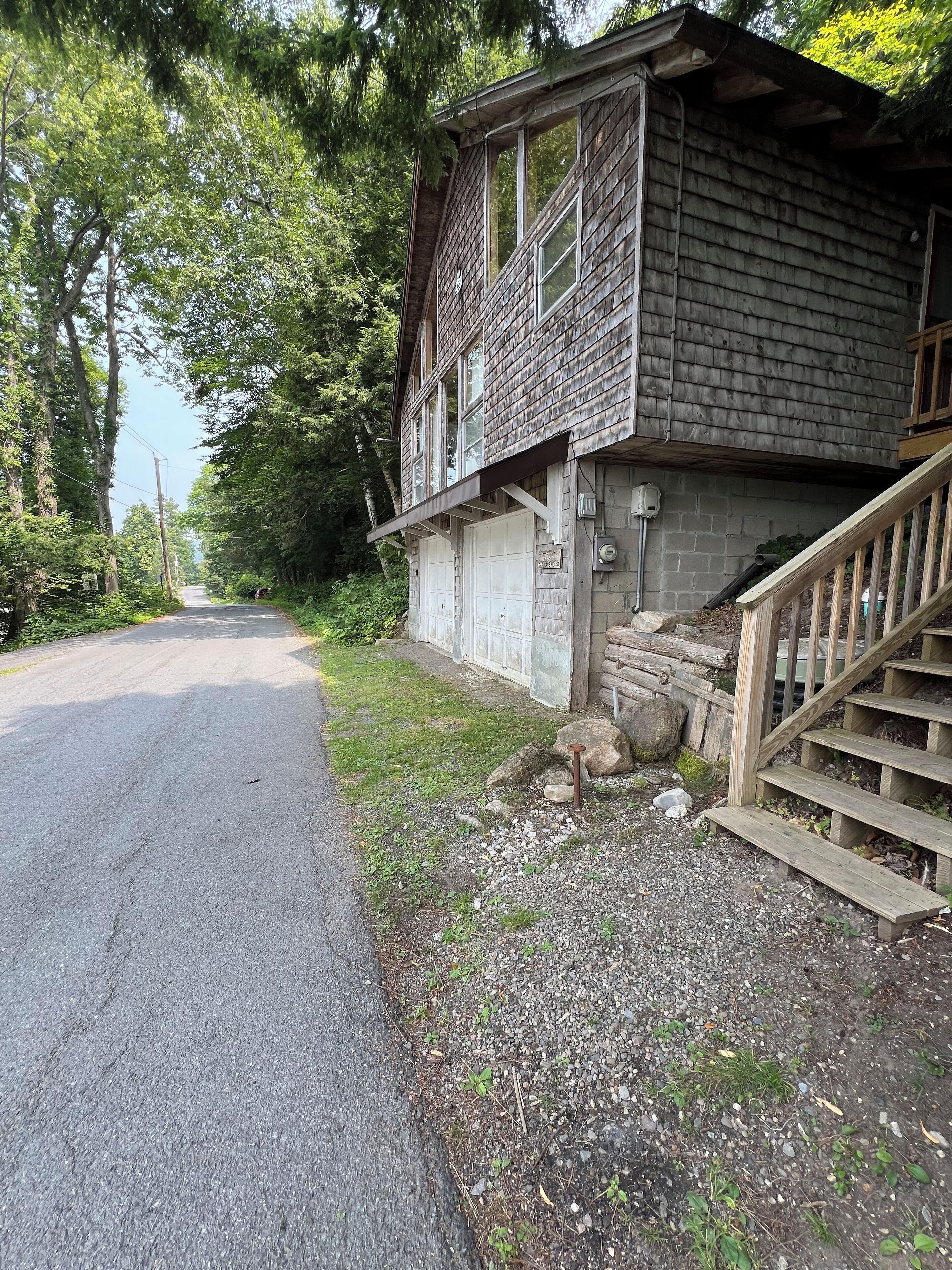 A rustic cabin with a wooden exterior, a front porch, and a staircase leading to the entrance.