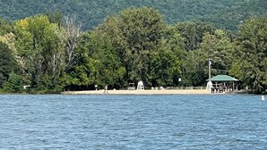 A beach with a lifeguard tower, a pavilion, and dense forest in the background.
