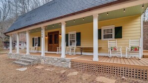 A covered porch with white rocking chairs and a stone staircase leading to the door. - Over Yonder (Leipers Fork)
