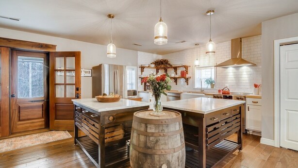 A spacious kitchen with a large island, wooden cabinetry, and pendant lighting. - Over Yonder (Leipers Fork)