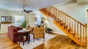 A spacious living room with a wooden staircase, a ceiling fan, and a fireplace. - Over Yonder (Leipers Fork)