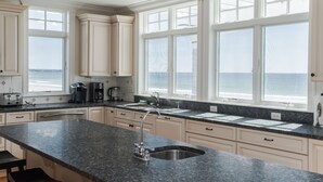 Una cocina con amplios ventanales, encimera de granito y muebles de color blanco.