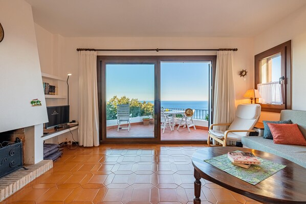A hotel room with a balcony, a sofa, a coffee table, and a TV.