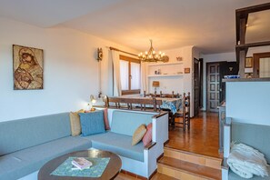 A living room with a sofa, a coffee table, and a dining area with a chandelier.
