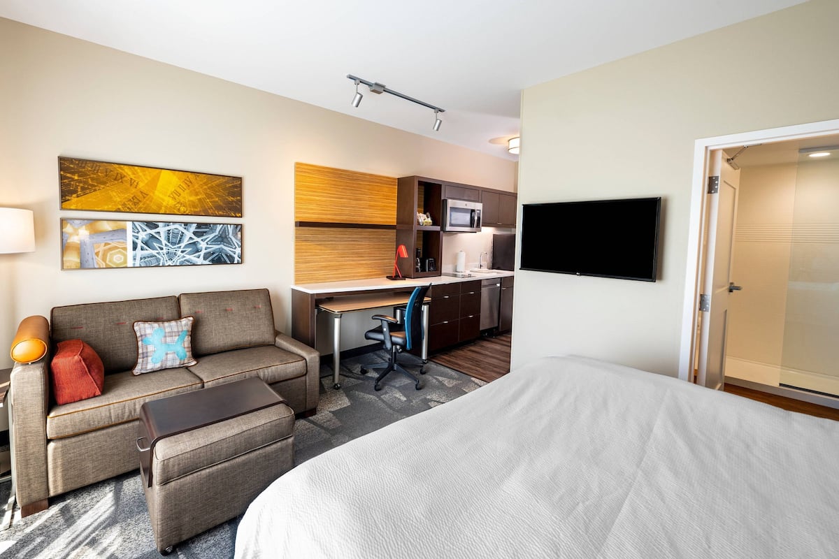 Hotelkamer met een bed, een slaapbank, een bureau, een stoel, een televisie en een magnetron.