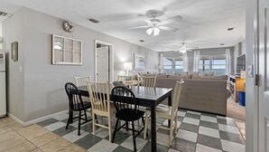 A dining area with a black table and chairs, a ceiling fan, and a checkered floor.