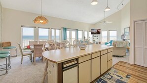 Amplia sala de estar con una isla grande, sillas de comedor y vista al océano.