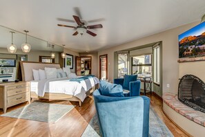 A spacious bedroom with a large bed, a ceiling fan, and a fireplace.