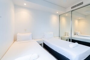 Une chambre d’hôtel avec deux lits simples, un grand miroir et une armoire.