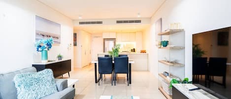 A modern living room with a sofa, coffee table, and a dining area with chairs and a table.