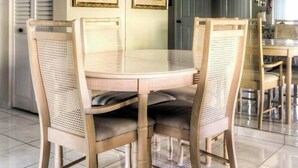 Een eethoek met een ronde tafel en vier stoelen, een kroonluchter en twee ingelijste foto's aan de muur.